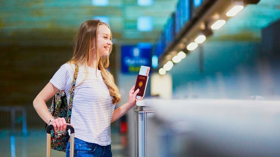 Capa principal - Pessoa em um aeroporto com passaporte vermelho