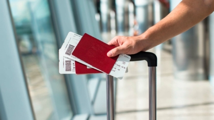 Capa Principal - Mãos masculinas segurando passaporte e passagens