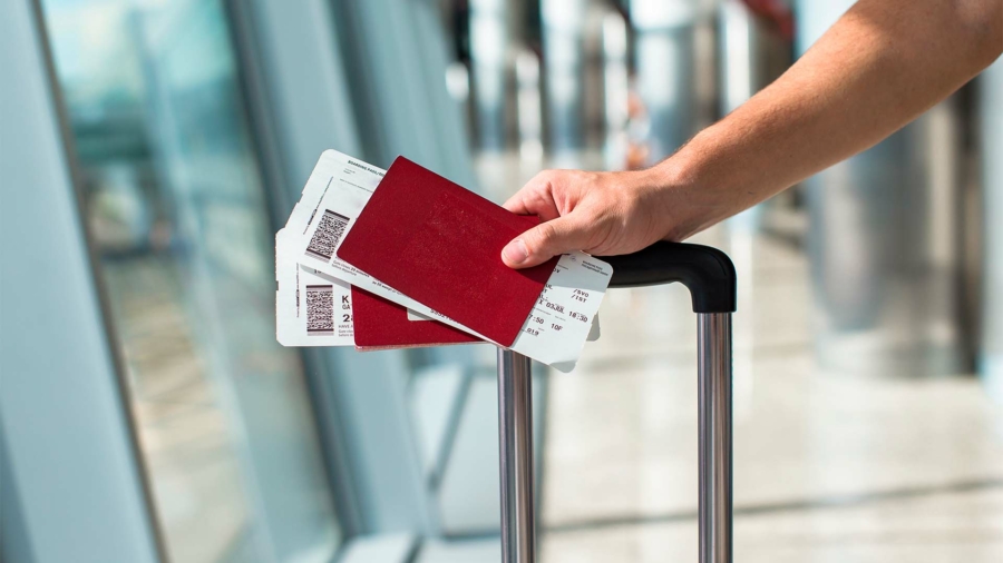 Capa Principal - Mãos masculinas segurando passaporte e passagens